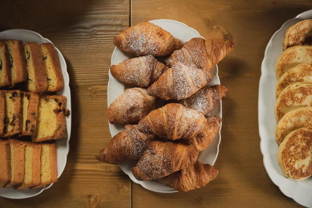 Vassoi di dolci per la colazione con plumcake, cornetti spolverati di zucchero e pancake