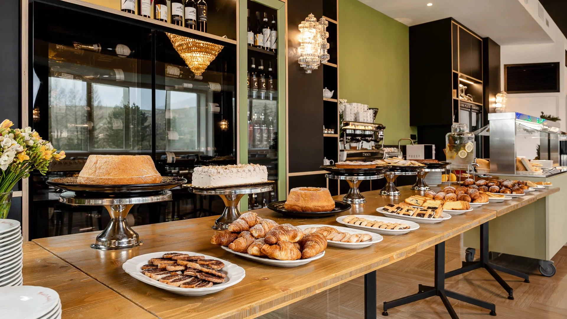 Buffet dolci della colazione con torte, cornetti e crostate esposti su tavolo di legno