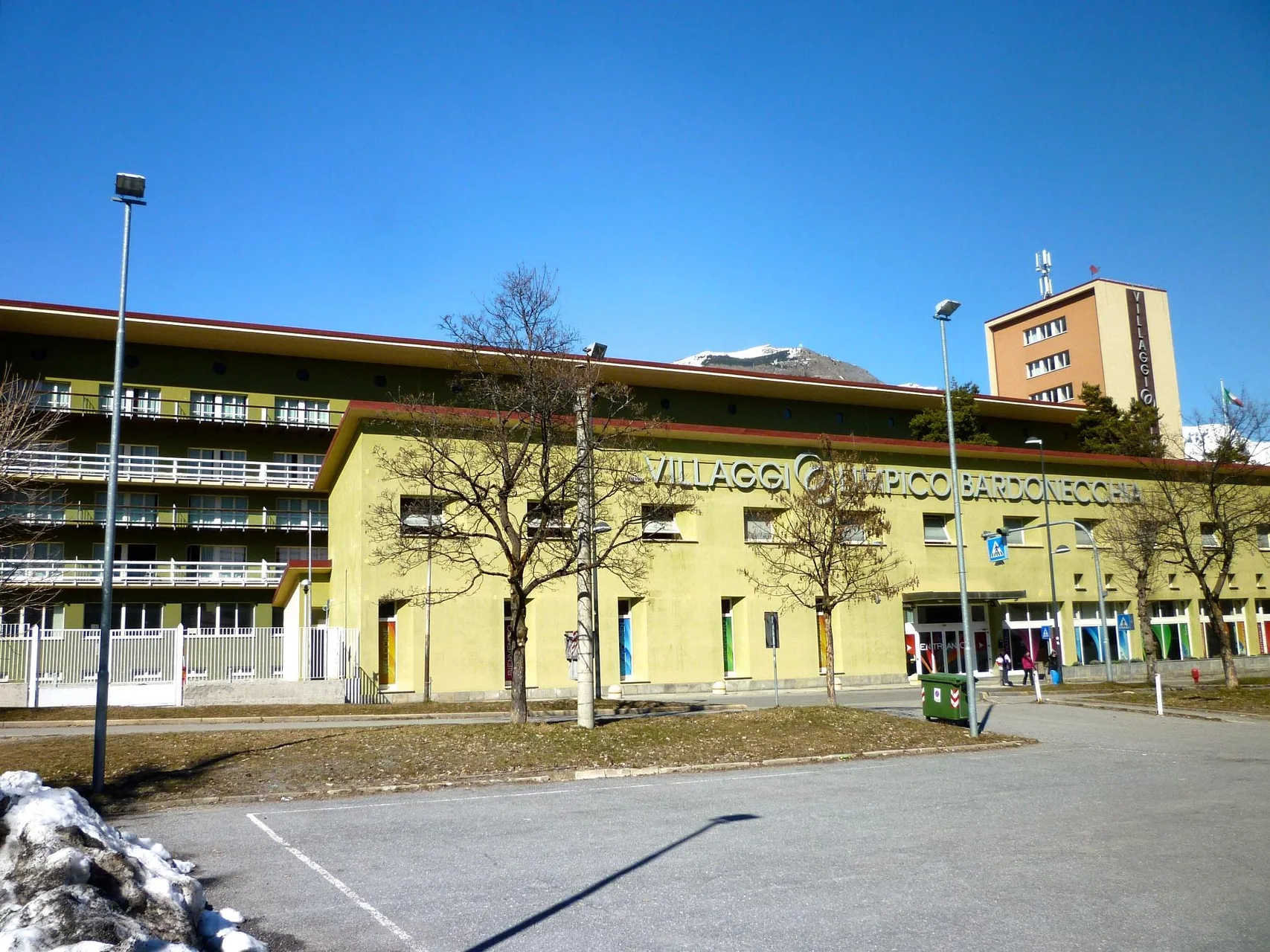 Facciata verde del Villaggio Olimpico Bardonecchia con montagne sullo sfondo