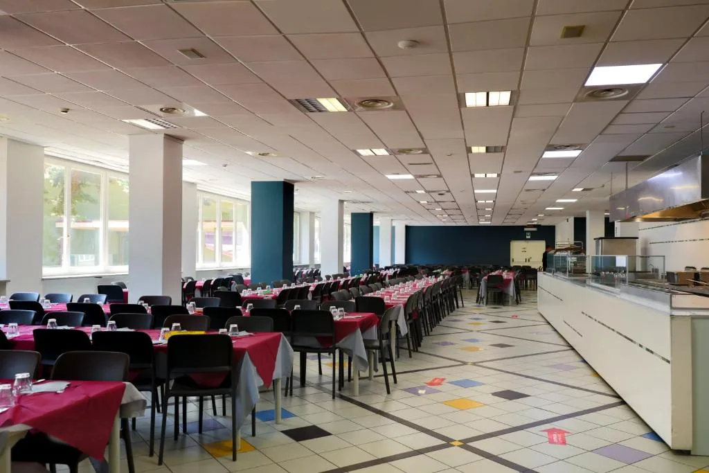 Sala ristorante ampia con tavoli apparecchiati con tovaglie rosse