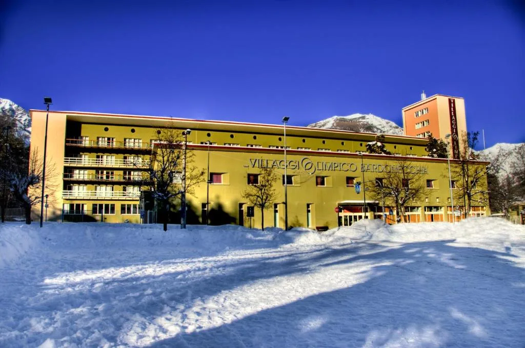 Facciata gialla dell'hotel innevata sotto cielo azzurro