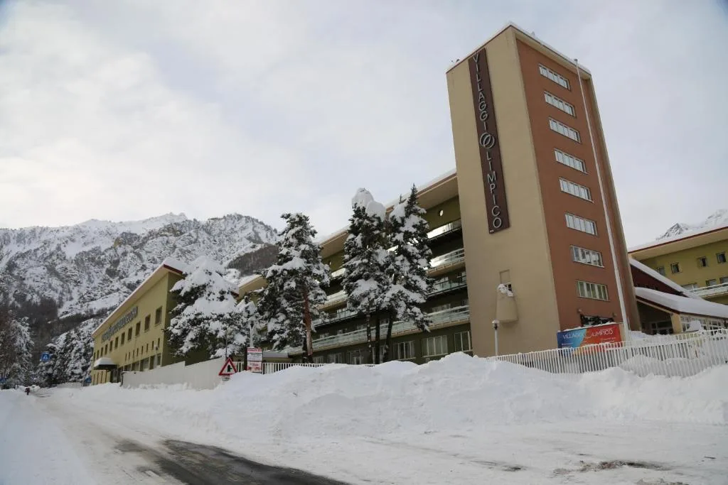 Esterno dell'hotel con torre e cumuli di neve in inverno