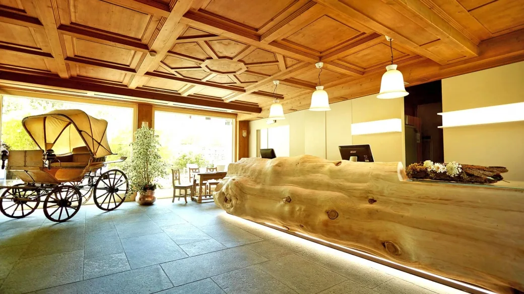 Reception con bancone in tronco di legno, soffitto a cassettoni e carrozza d'epoca