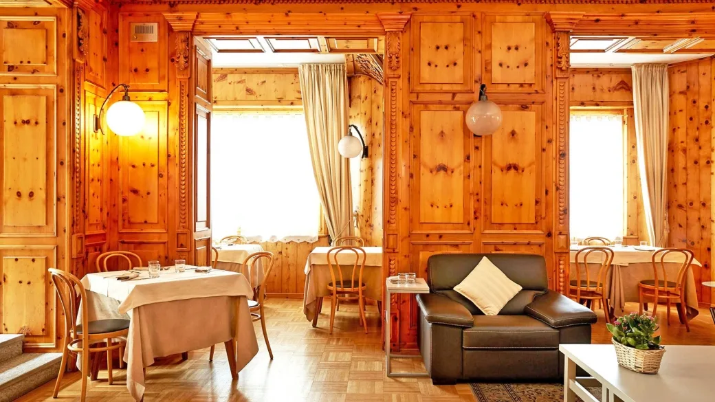 Sala da pranzo rivestita in legno con tavoli apparecchiati e poltrona in pelle