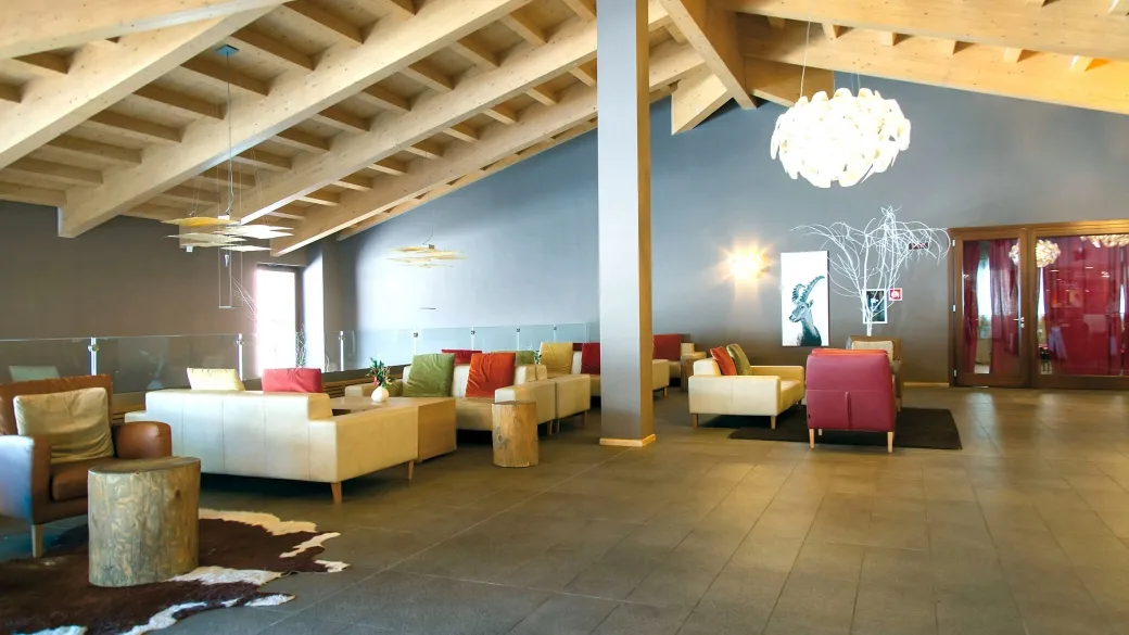 Lounge dell'hotel con soffitto in travi di legno, divani e poltrone confortevoli