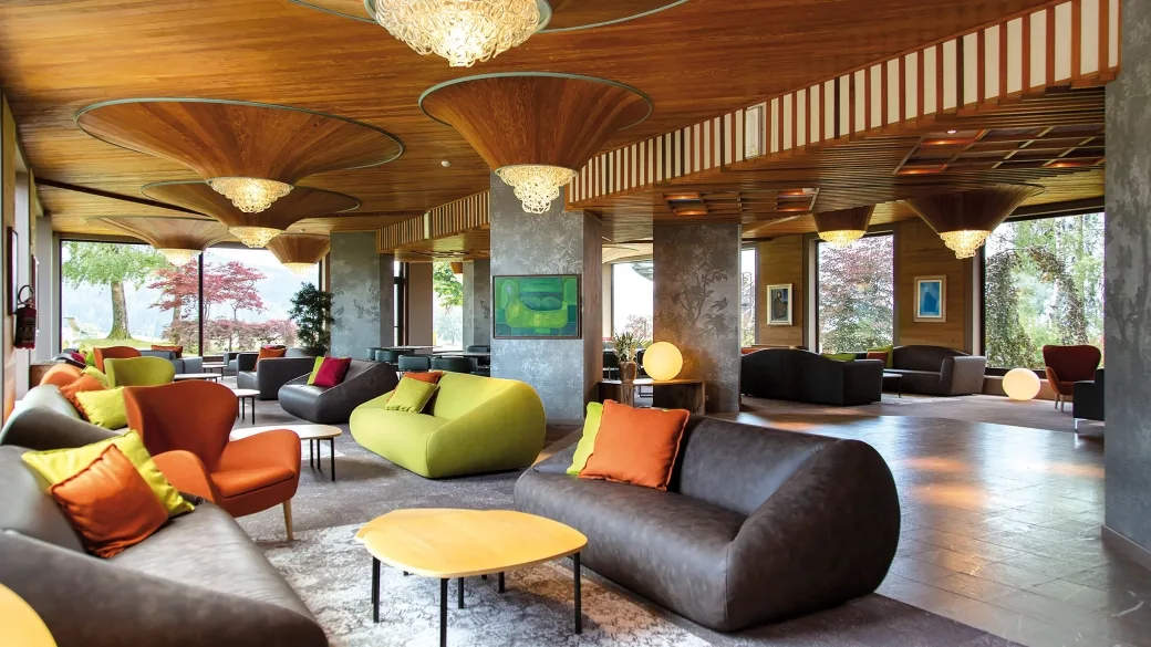 Ampia hall lounge con divani colorati, poltrone e soffitto in legno di design